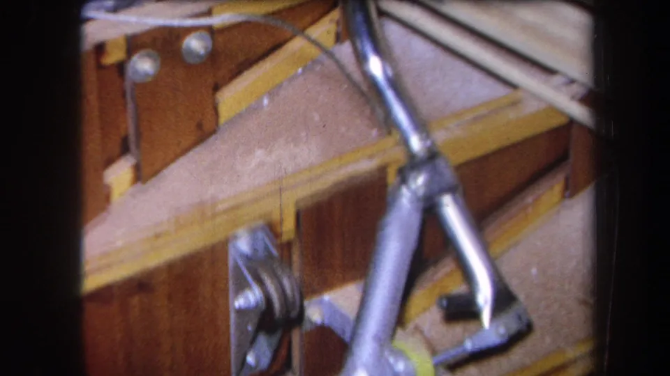 Angled 1964 Yucaipa frame with wood panels, silver tubing, rods, and mounted hardware in a tight workshop-like view.