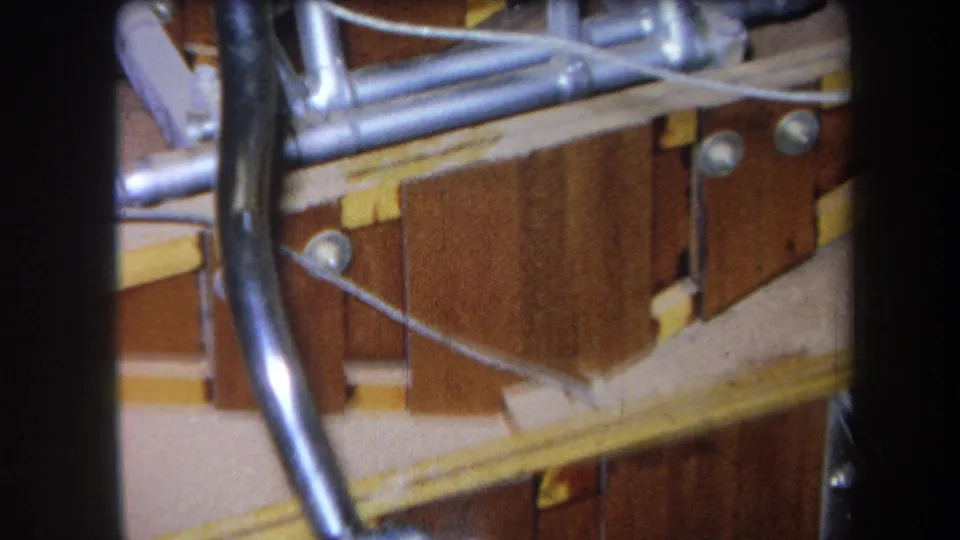1964 Yucaipa frame showing a board-mounted mechanical control area with silver pipes, rods, bolts, black cable, and yellow hardware.