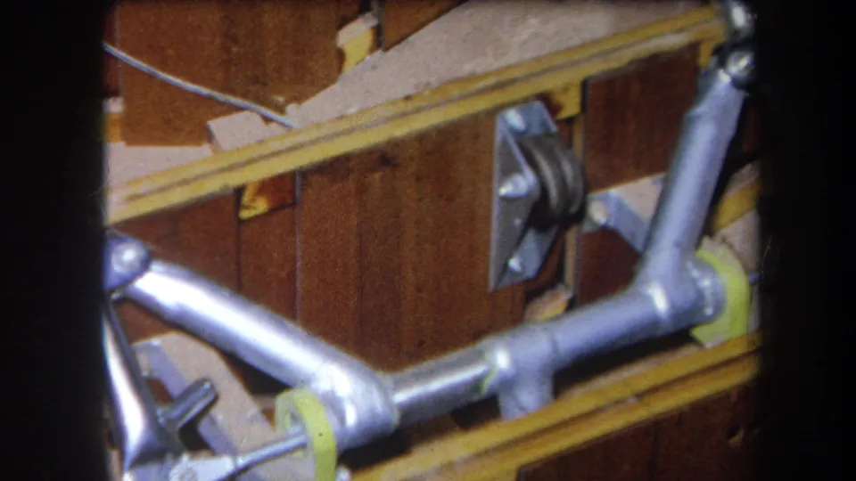 1964 Yucaipa 8mm frame with silver pipe tubing, a mounted bracket, yellow rails, and brown wood panel surfaces.
