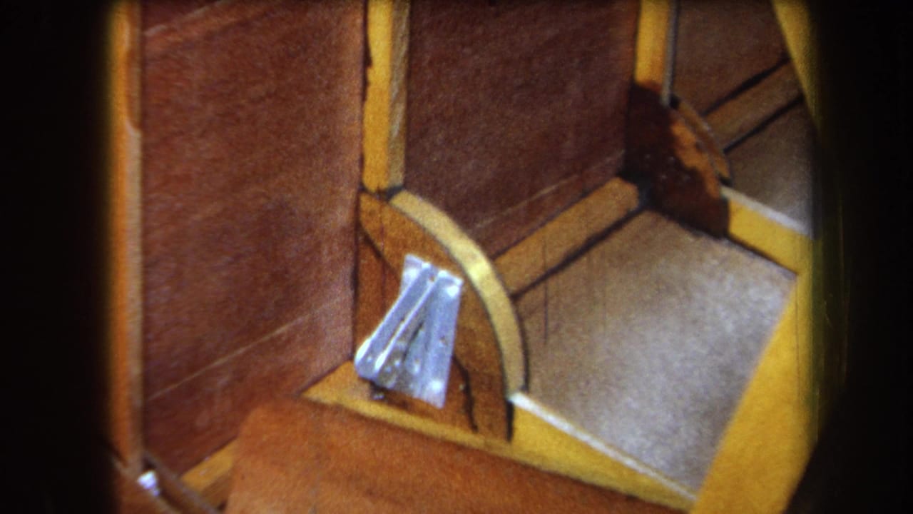 Similar close-up of wood paneling, yellow trim, gray surface, and silver bracket.
