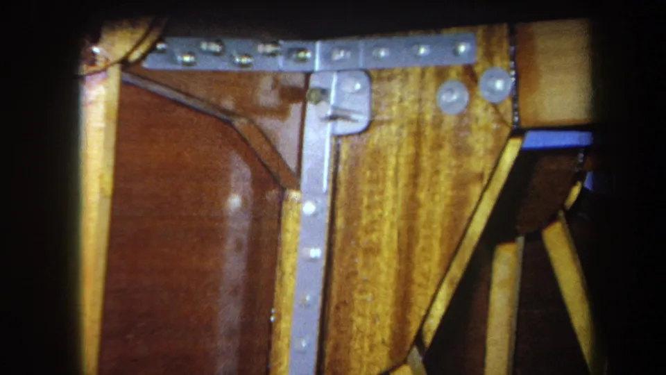 Final 1964 Yucaipa frame holds on yellow boards, a brown panel, metal fasteners, and shadowed structural gaps.