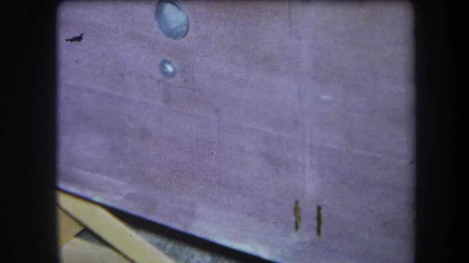 1964 8mm home-movie frame from Yucaipa showing a stained wooden picnic table surface with water spots, scratches, and soft focus.