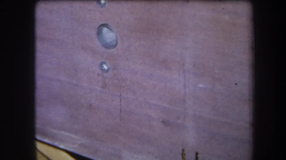 1964 Yucaipa 8mm frame of a purplish-brown picnic table top with circular water marks, stains, and rounded frame borders.