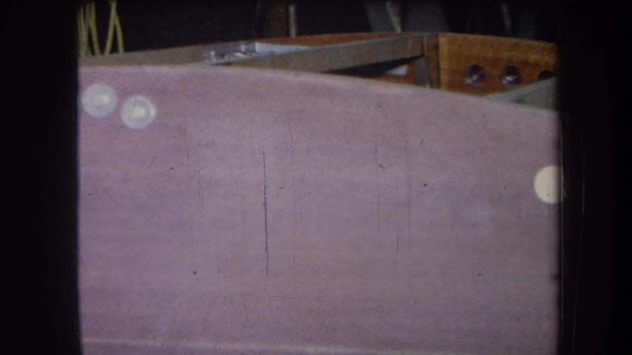 1964 Yucaipa-area 8mm frame showing a pale purple painted surface beneath exposed wood and metal hardware.