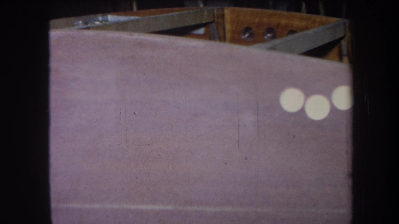 8mm close-up of the painted panel and upper wood structure, with white light reflections near the right edge.