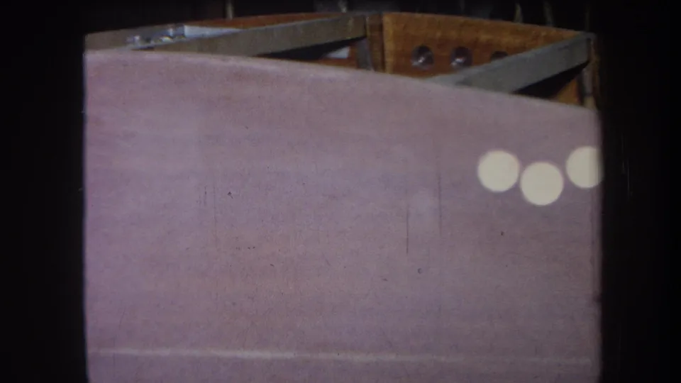 8mm close-up of the painted panel and upper wood structure, with white light reflections near the right edge.