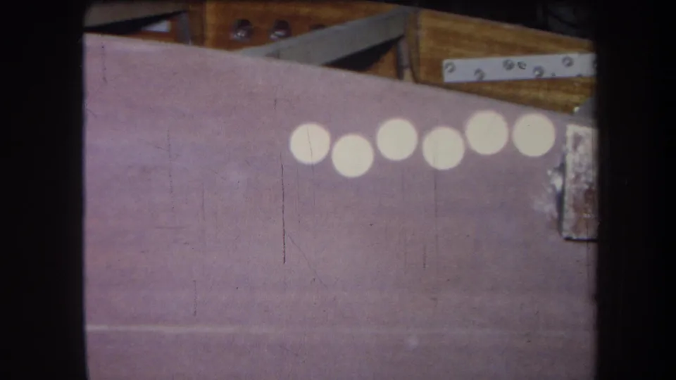 Yucaipa 1964 home-movie close-up of a painted construction surface with wood, metal fittings, and bright reflected circles.