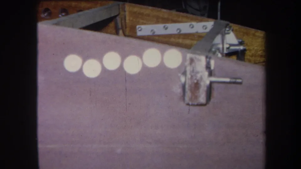 The frame holds on the same purple surface, with six pale circles, a worn latch, screws, and wood visible near the top edge.