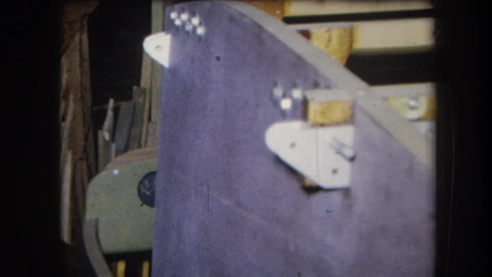 Soft 8mm frame from 1964 showing purple-painted wood, white metal fittings, and cluttered lumber in Volmer Yucaipa.