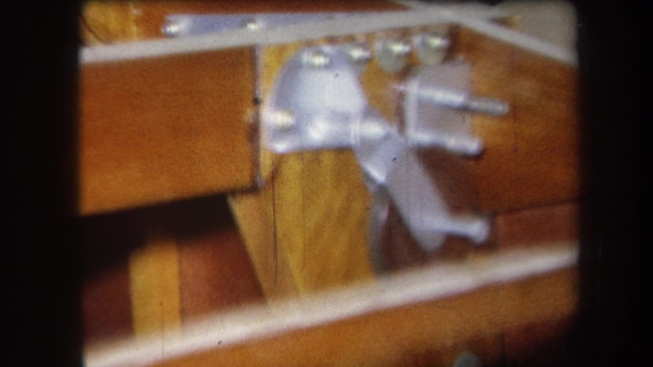Close 1964 home-movie view of silver hinge hardware, bolts, and varnished wooden rails or panels in Yucaipa, California.