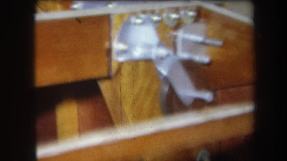 Close 1964 Yucaipa 8mm view of a metal bracket fastened to wooden machinery or display components.
