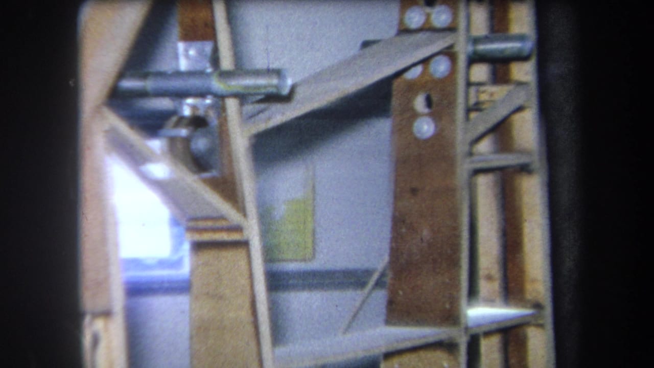 Static view of wooden shelves, metal rods, and wall-mounted supports.