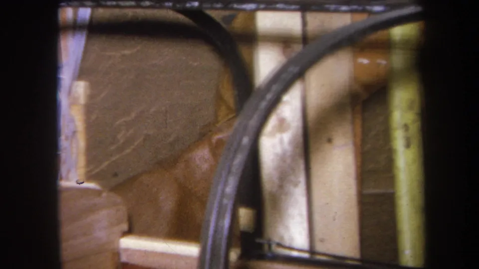 1964 Yucaipa home-movie frame showing a close storage detail with wood panels, curved tubing, and pale vertical supports.