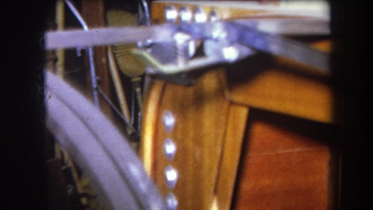 1964 8mm close-up of metal rail hardware and bolts mounted against varnished wood construction surfaces.
