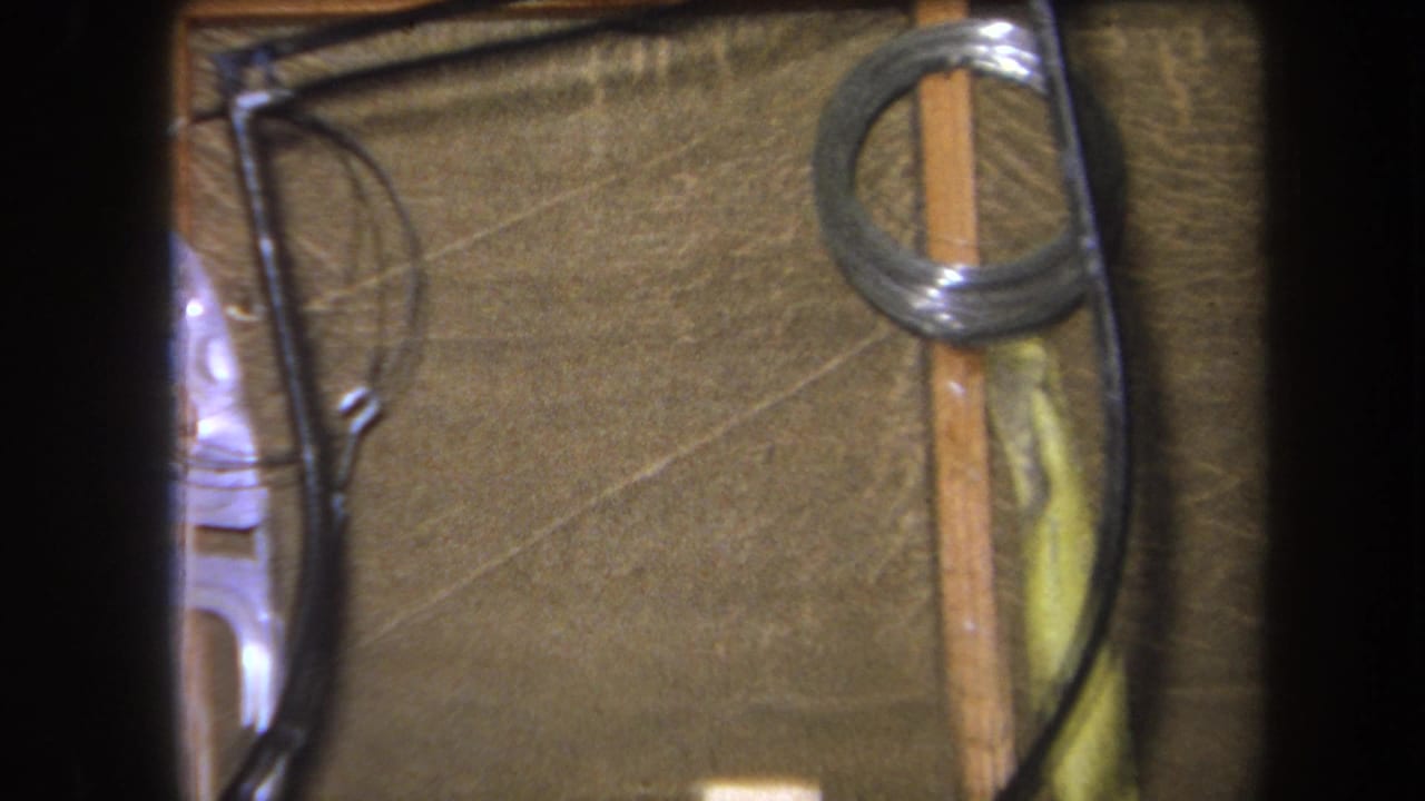 Textured brown wall with wood strips, black wires, and a coiled metal spring near the top right.