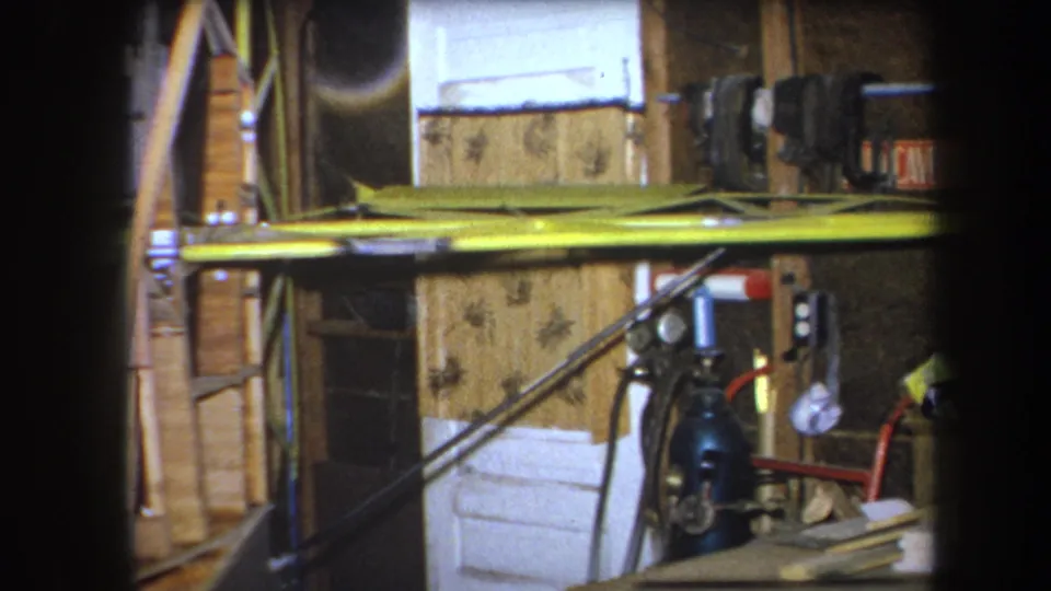 1964 Yucaipa frame showing a wider interior workspace with cables, yellow boards, tools, white block or panel material, and wood surfaces.