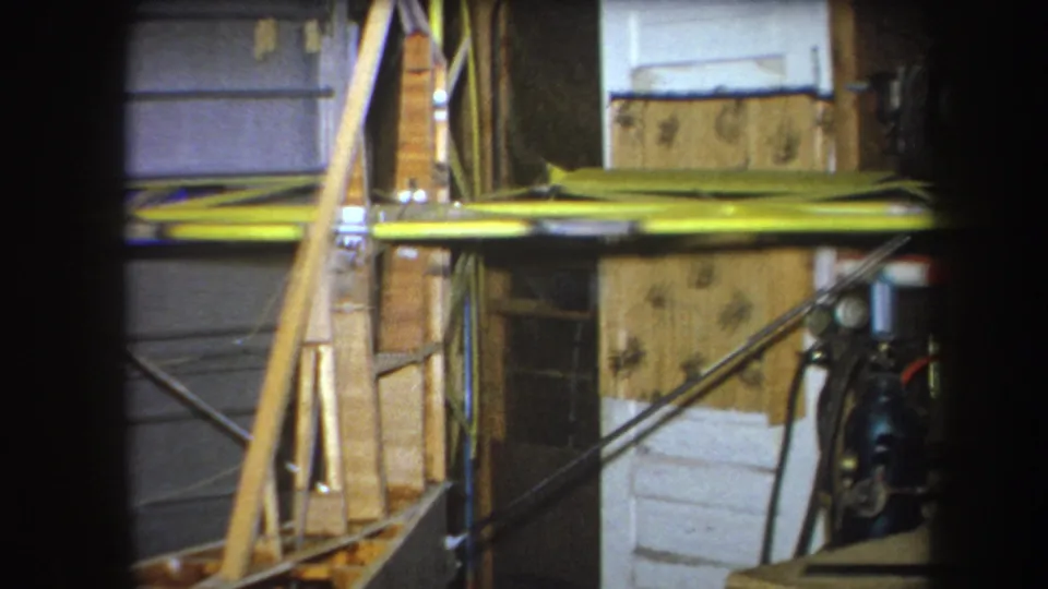 1964 Yucaipa construction frame with diagonal wood supports, yellow horizontal bracing, gray panels, and unfinished wall materials.