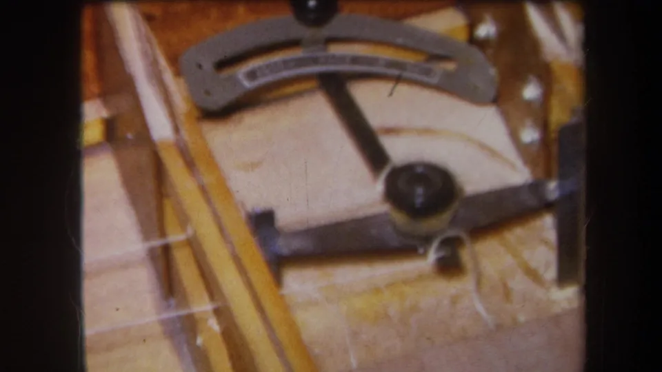 1964 8mm workshop frame from Yucaipa showing a curved measuring gauge, black adjustment knobs, and wood surfaces.
