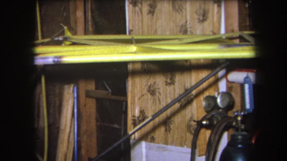 Static 1964 workshop view in Yucaipa, with a yellow metal beam across the frame and a green gas cylinder with pressure gauges at right.