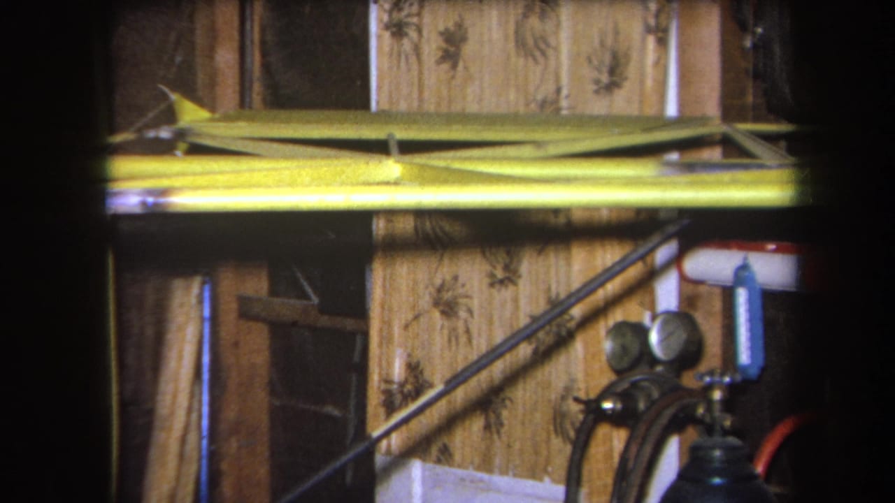 Yellow model aircraft part spans the upper frame, with wood paneling, shelf supports, and gauges at lower right.