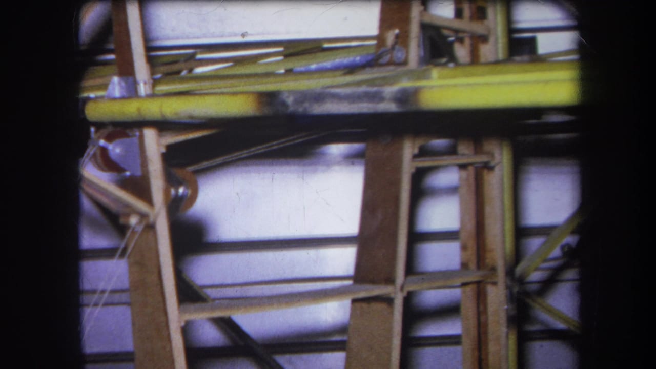1964 Yucaipa-area 8mm frame showing wooden bracing, yellow metal rails, and exposed industrial equipment details.