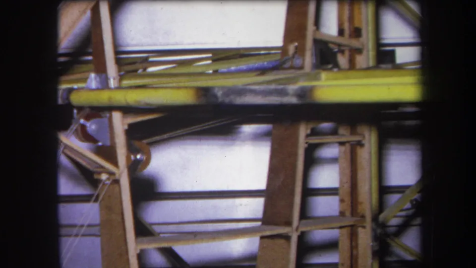 1964 Yucaipa construction-site frame showing a scaffold-like wooden structure, yellow rail, and exposed metal rods.