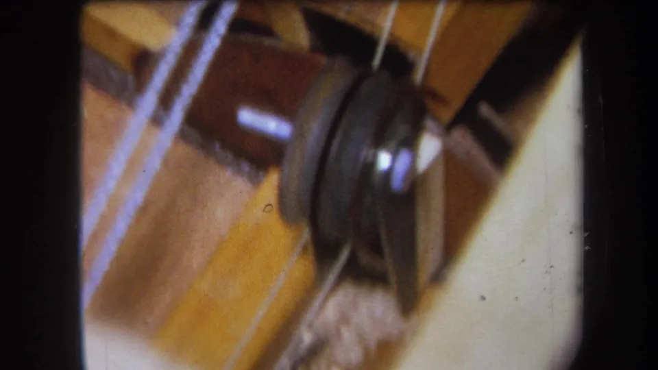 1964 Yucaipa frame showing the spinning disc and yarn close to warm wooden boards in a small winding or textile setup.