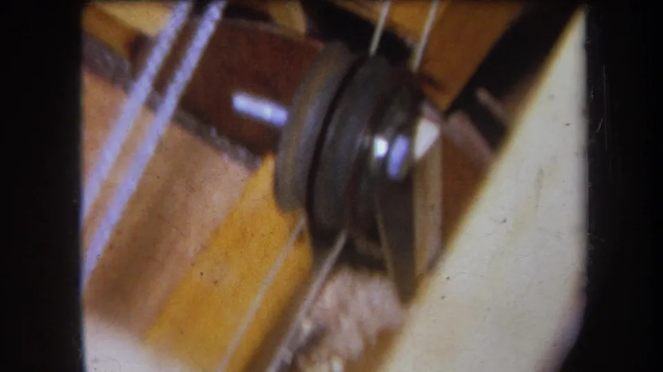 1964 8mm close-up from Yucaipa-area footage showing pulley hardware and thread on a vintage sewing machine.