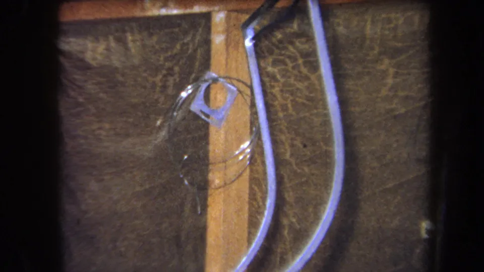 1964 Yucaipa-area home-movie frame of clear tubing, a wooden board, and a small square plastic fitting on a dark background.