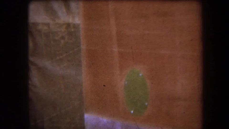 1964 8mm frame from Yucaipa metadata showing a close reddish painted hull-like surface with a green oval fitting and dark film edge.