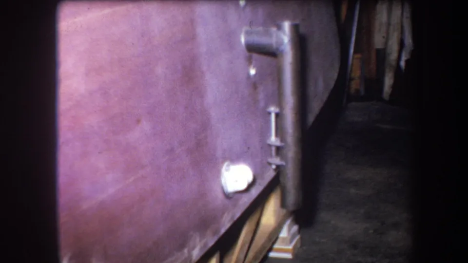 Final 1964 8mm frame showing the purple-tinted boiler surface, white circular fitting and pipework in a dim Yucaipa utility space.