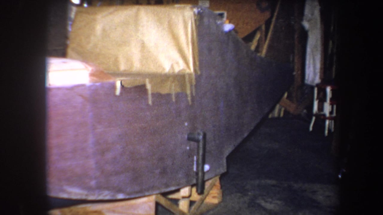 1964 Yucaipa 8mm frame with taped brown covering over a large object, set near dark workshop materials.