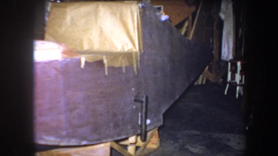 1964 Yucaipa 8mm frame showing the tarp-covered object from a similar angle, with tape hanging from the lower edge.