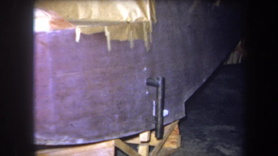 1964 Yucaipa 8mm frame with a closer view of taped tarp material, side hardware, and the dark workshop floor.
