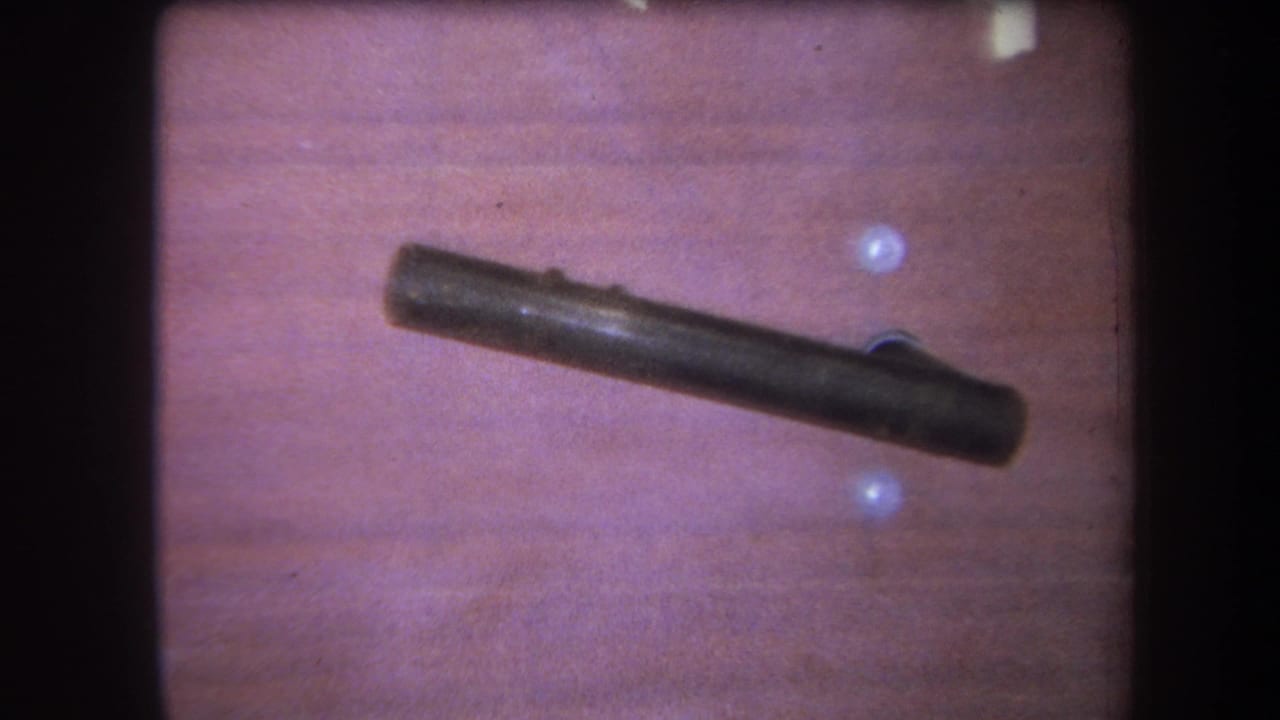 1964 Yucaipa interior detail with a dark rod or handle mounted across warm wood paneling and pale holes in the wall.