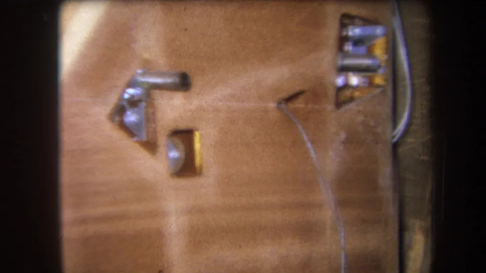 Final 1964 Yucaipa frame holds on a close view of wood grain, metal fixtures, and a thin wire, with the 8mm frame edge visible.