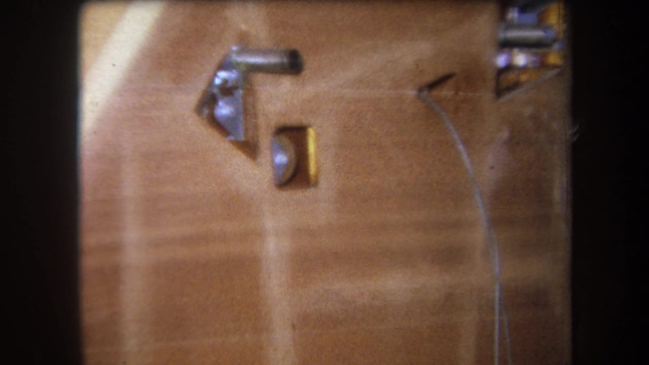 Wooden surface with metal parts, a brass-colored inset, and a curved wire.