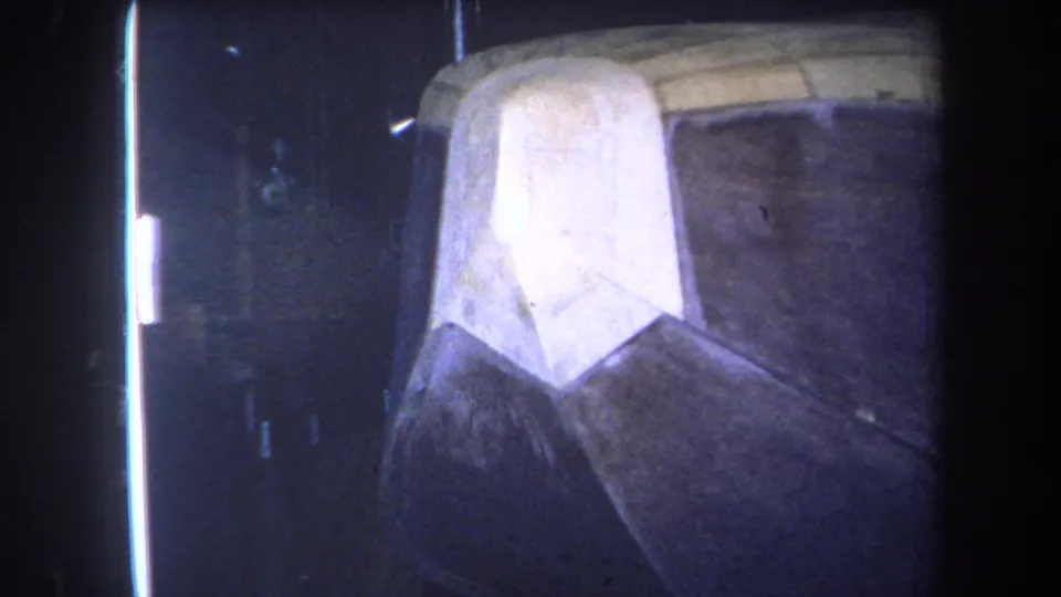 1964 Yucaipa-area home-movie frame showing pale material beside dark attic space and unfinished wood under faded 8mm color.