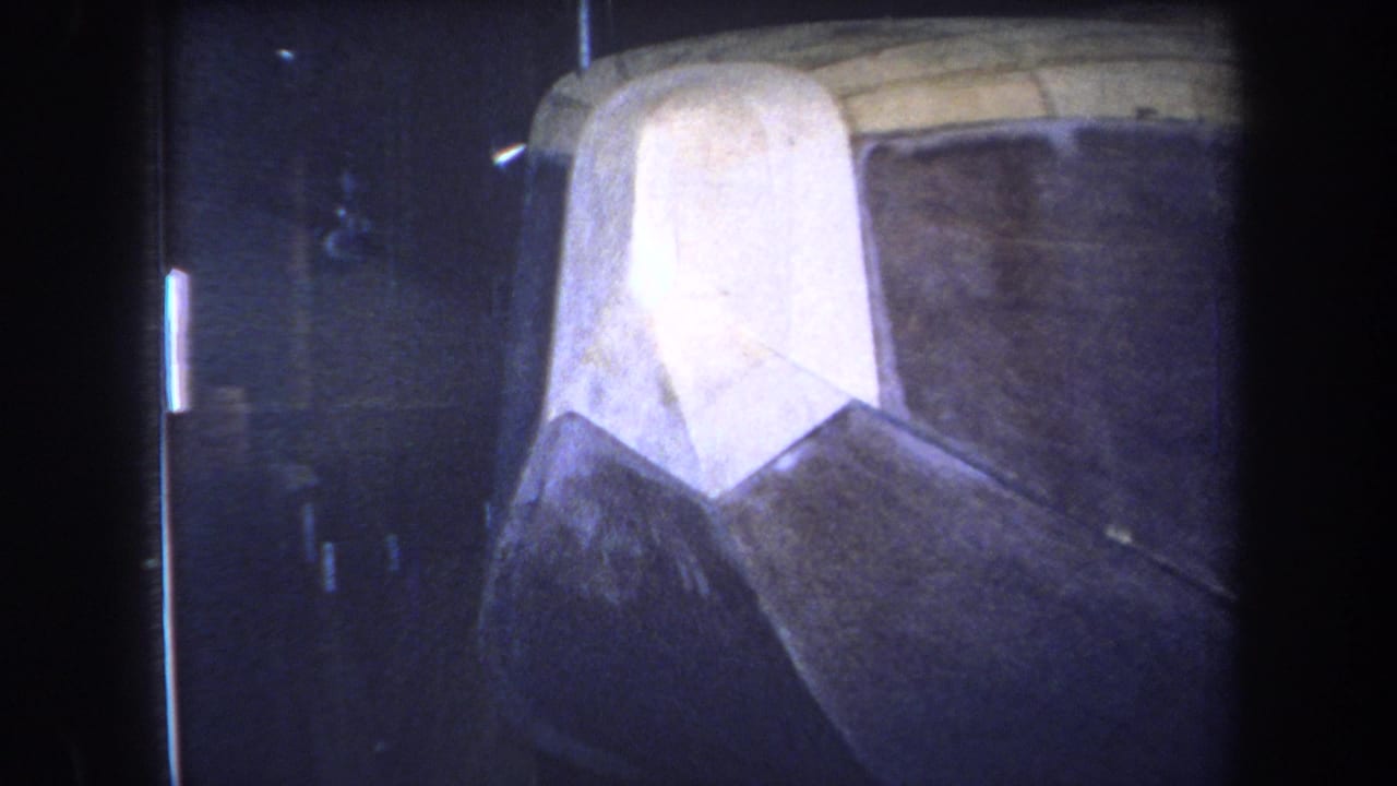 Close view of a weathered boat-like hull section in a dark indoor space.