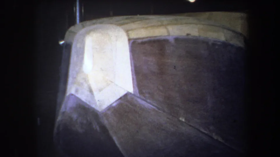 Final 1964 8mm frame holds on the aircraft nose and adjoining fuselage surface, with wood grain and panel seams visible in low light.