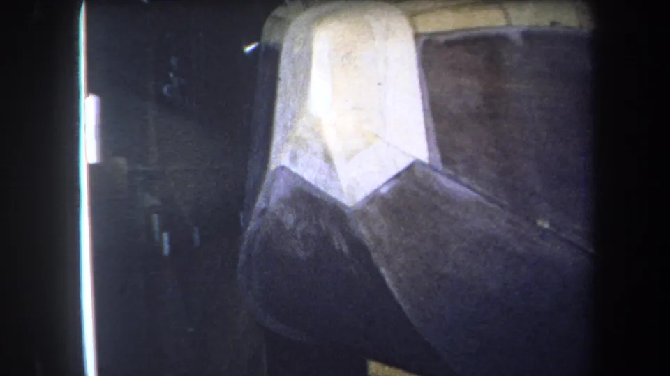 1964 Yucaipa 8mm frame showing the object shifted left, with bright edge light and textured brown surfaces visible.