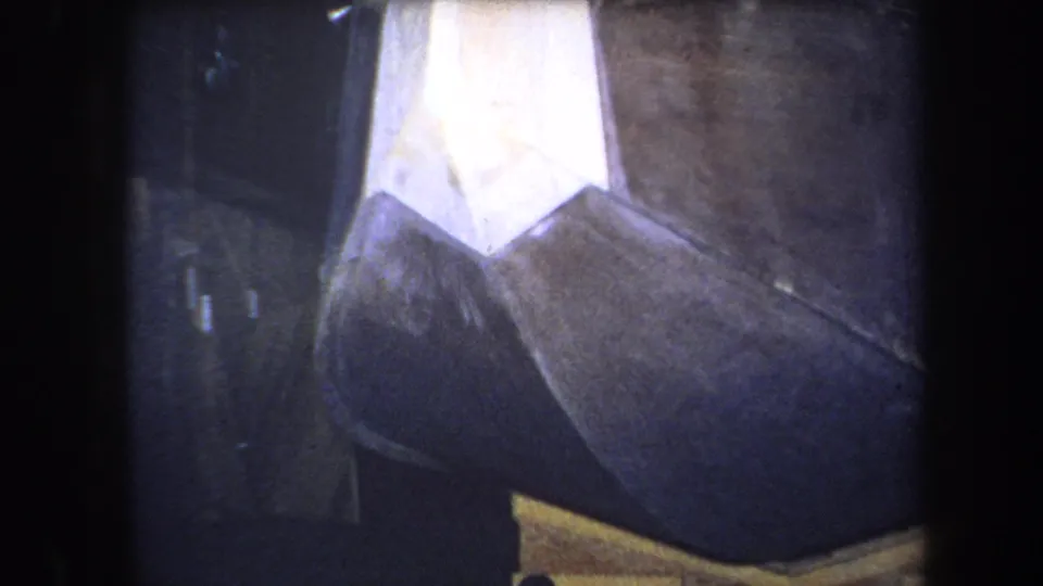 1964 Yucaipa home-movie frame showing a close-up of a geometric painted metal sculpture with dark, white, brown, and yellow planes.