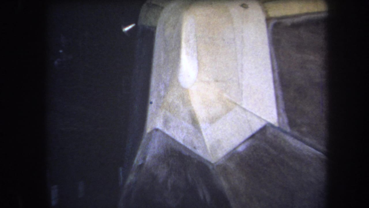 1964 Yucaipa home-movie close-up of a light plastic wall object with angular map-like seams and dark film edges.