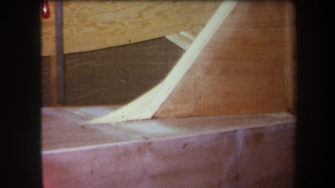 1964 Yucaipa-area 8mm frame with a pale chute-like piece crossing a wooden structure above a reddish platform.
