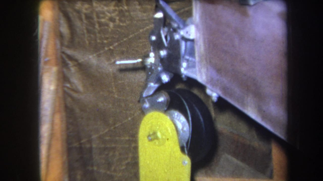 Close 8mm frame of the yellow handle, black wheel, and metal control parts, with the machine body cropped tightly at the right.
