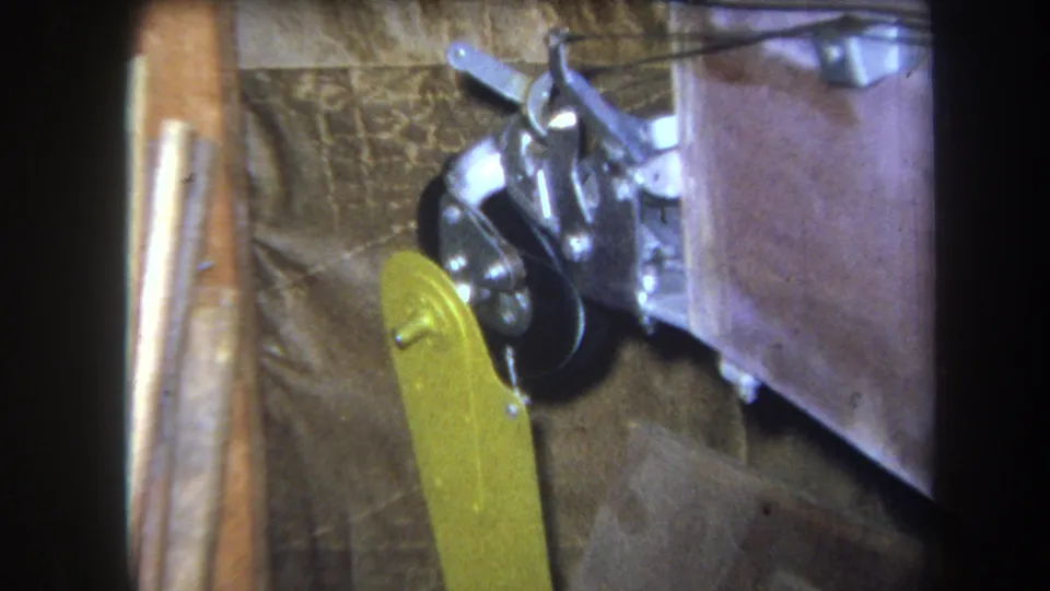Final 1964 8mm frame showing the yellow paddle attachment near a black pulley wheel and metal bracket assembly in Yucaipa metadata context.