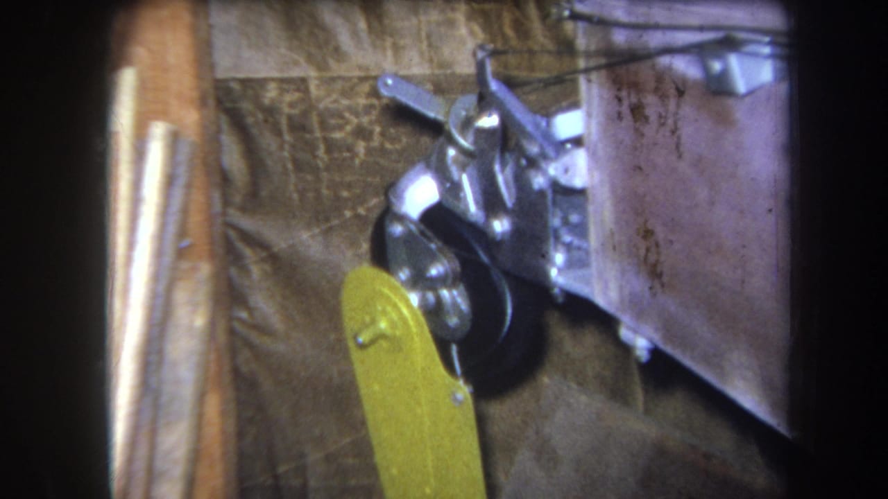 The yellow lever remains raised beside the black wheel and metal assembly against a brown backing.