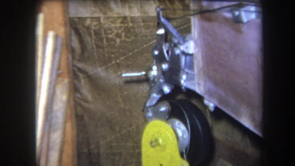 1964 Yucaipa 8mm frame ending on the static industrial component with yellow lever, wheel, bracket, and dark corner exposure.