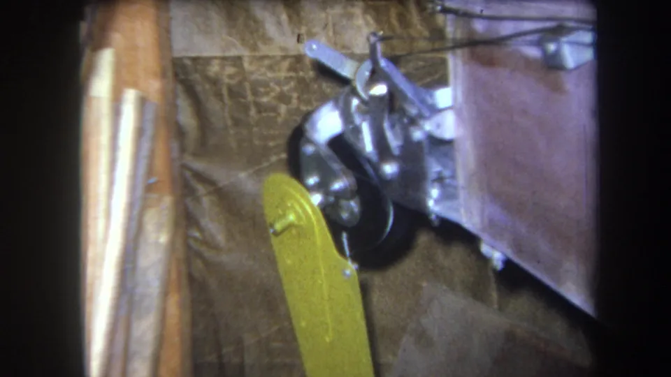 1964 Volmer, Yucaipa close-up of a yellow lever beside a black rotating component, silver hardware, and rough construction materials.