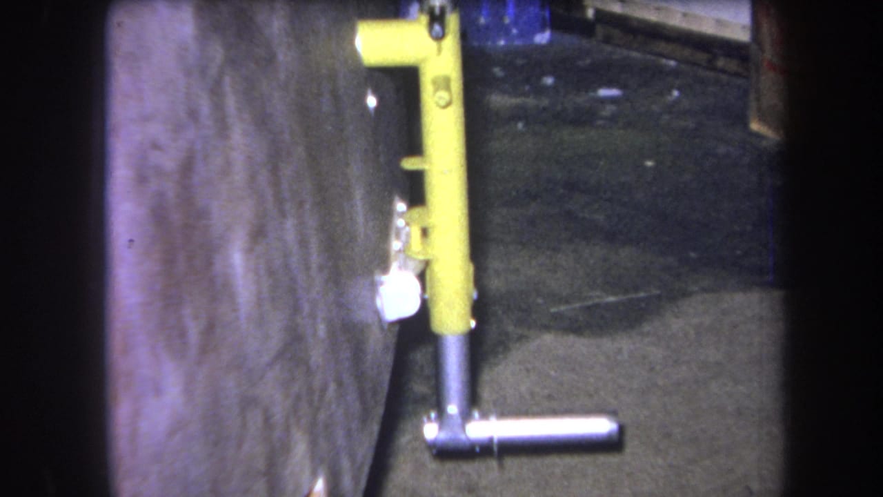 Yellow metal fixture and silver handle beside a rough concrete wall.
